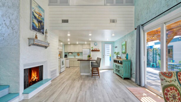 A spacious kitchen with a fireplace, wooden floors, and a dining area with a view. - Big Yard w/ Priv Pool, Firepit, Patio | Near the Beach | Reel Time by AvantStay (Port Aransas)