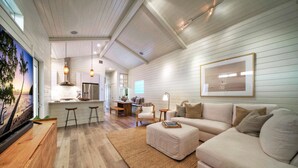 Ein großzügiger Wohnbereich mit einer großen Couch, einem Holztisch und einer Küche im Hintergrund.