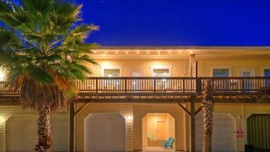 A two-story building with a balcony, a covered porch, and a garage. - Pool, Walk to Old Town + Eateries, Nightlife, Shopping | Rock N Reelby AvantStay (Port Aransas)