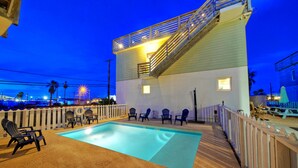 A pool area with chairs and a staircase leading to an upper deck. - Stella Maris by AvantStay | Rooftop View + Pool (Port Aransas)