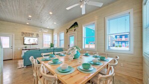 Uma sala de jantar com uma mesa de madeira posta para quatro pessoas, rodeada por seis cadeiras.