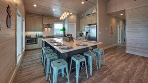 Una cocina amplia con una isla central, piso de madera y armarios de color claro.