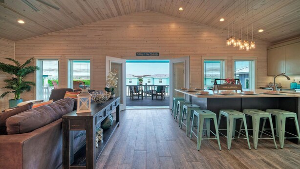 Amplia sala de estar con techo de madera, un sofá, una mesa de centro y vistas al exterior.