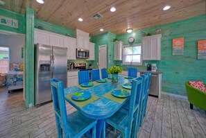 Une cuisine aux murs de couleur turquoise, avec des meubles blancs et un ensemble de salle à manger bleu.