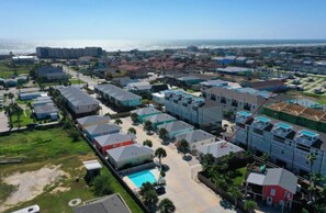 Un quartier résidentiel situé sur la côte, composé de plusieurs immeubles d’appartements, d’une piscine et offrant une vue sur l’océan.