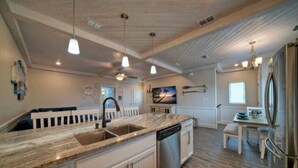 A kitchen with a marble countertop, stainless steel appliances, and a wooden ceiling.