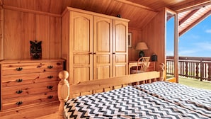 Ein Schlafzimmer einer Holzhütte mit Bett, Schminktisch und offener Balkon.