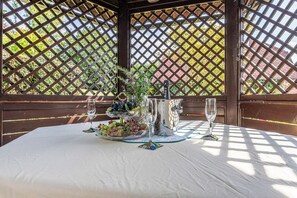A table set for two with a white tablecloth, a pitcher, a bowl of fruit, and two wine glasses. - Pool Chalet Adonis w/ Panoramic Views (Semič)