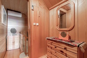 A wooden cabin interior with a wooden dresser, a mirror, a fan, and a door leading to a balcony. - Pool Chalet Adonis w/ Panoramic Views (Semič)
