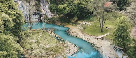 Un río serpentea por una zona boscosa con un acantilado rocoso y un pequeño edificio cerca del agua.