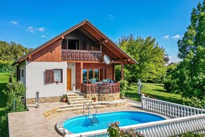 Une maison à deux étages dotée d’une piscine, d’un balcon et d’un escalier en pierre menant au deuxième étage.