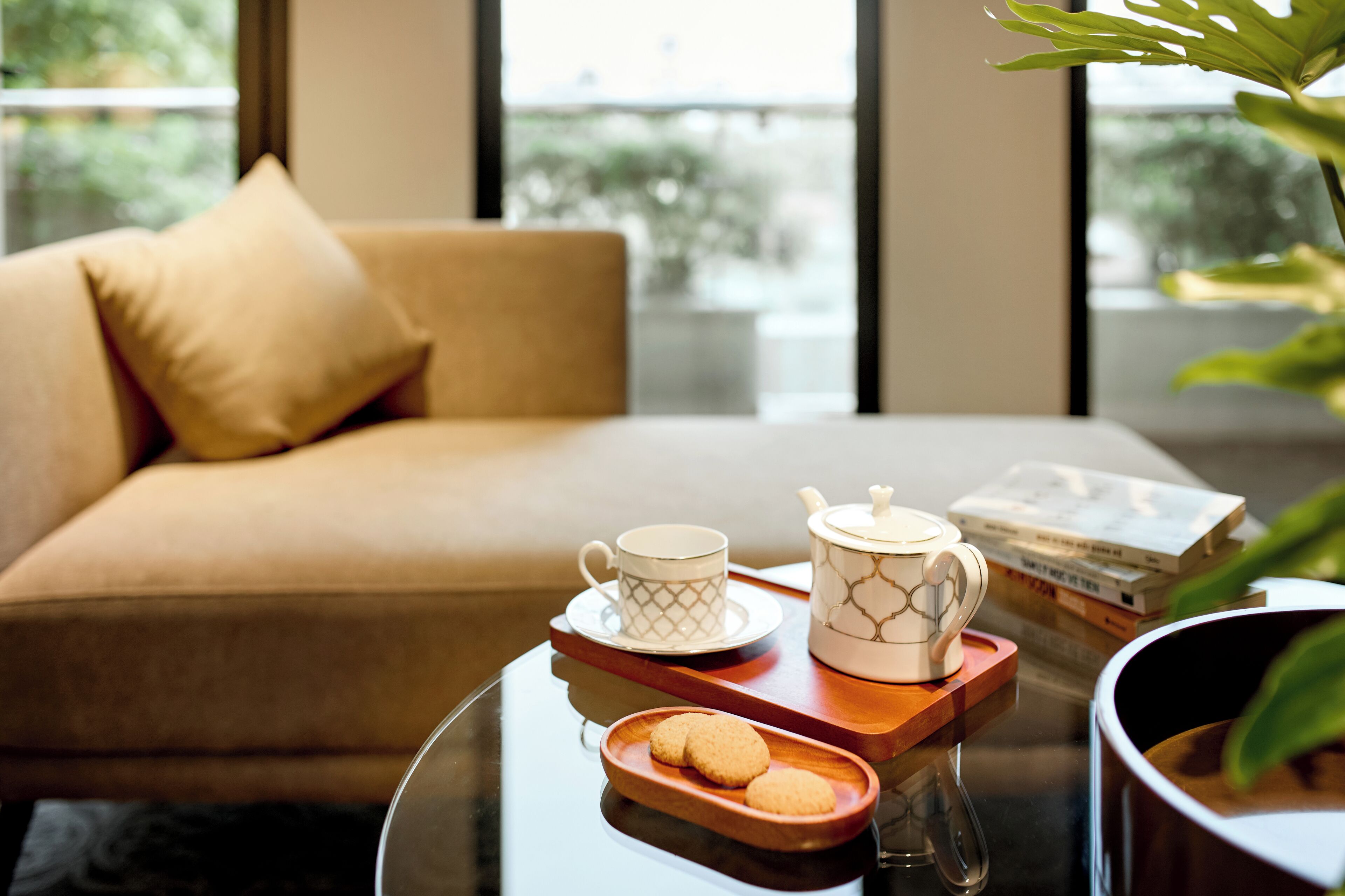Un salon moderne avec un canapé, une table basse sur laquelle se trouve un plateau avec une théière, des tasses et des biscuits.