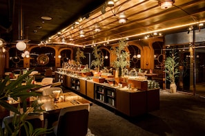 A hotel lobby with a long reception desk, multiple seating areas, and a variety of plants.