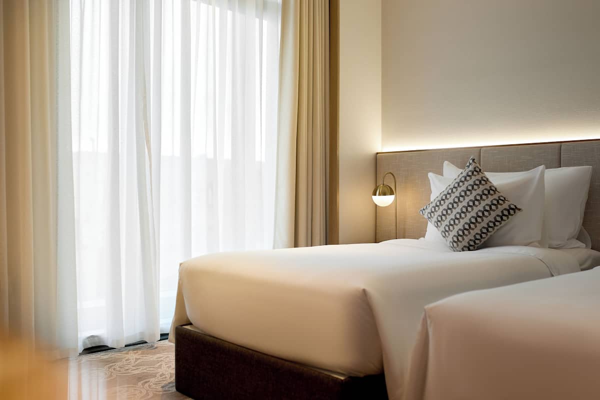 A hotel room with a large bed, a bedside table, and a lamp.
