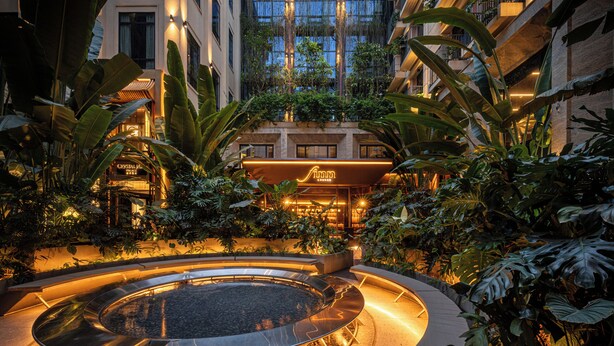 A circular water feature surrounded by plants and a building with a sign. - REY Hotel Hanoi (Hanoi)