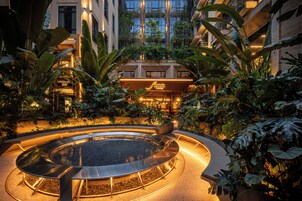 A circular water feature surrounded by plants and a building with a sign.