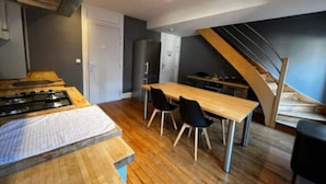 Una cocina compacta con estufa a gas, refrigerador y mesa de comedor con sillas.