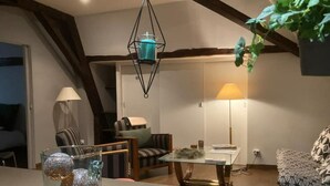 Una sala de estar acogedora con un sofá, sillones, una mesa y una lámpara colgante.