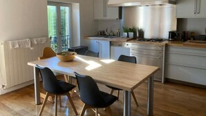Una cocina moderna con una isla central, electrodomésticos de acero inoxidable y un comedor con mesa y sillas de madera.