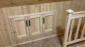 A wooden cabin interior with a built-in cabinet and a small white object on the railing. - Bakhmaro (Bakhmaro)