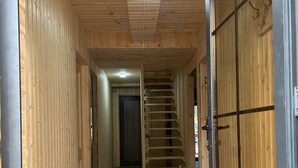 A wooden interior hallway with a central staircase, wooden walls, and a door with a metal frame. - Bakhmaro (Bakhmaro)