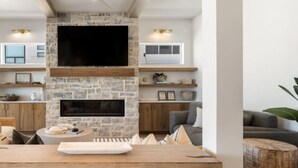 Une cuisine moderne avec un mur en pierre, un téléviseur encastré et des tabourets de bar.