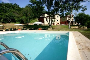 Relax by the pool surrounded by lush greenery and traditional architecture.