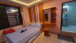 A bedroom with a bed, a small stool, a vanity with a mirror, and a bathroom visible through an open door. - York  Air Home (Kathmandu)