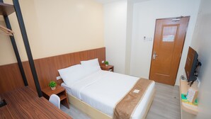 A neatly arranged hotel room with a bed, bedside table, a small desk, and a television. - Sundaze Dormitel (Naga)