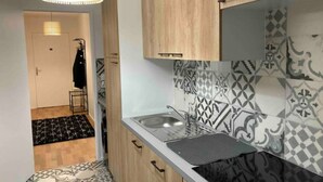 Une cuisine de taille réduite, avec des carreaux décoratifs, des armoires en bois et un luminaire suspendu.
