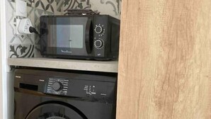 Une cuisine compacte équipée d’un four à micro-ondes et d’un lave-linge à chargement frontal.