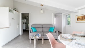 Un salon moderne avec un canapé gris, une table basse et une table à manger préparée pour deux personnes.