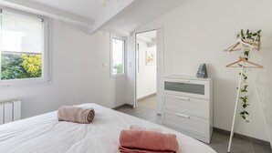 Une chambre à coucher avec un lit, une commode, un miroir et une fenêtre.