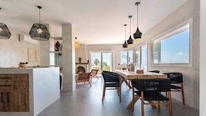 Une cuisine moderne dotée d’un îlot central, de luminaires suspendus et de grandes fenêtres.