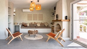 Un salon moderne avec un canapé, deux fauteuils en bois, une table basse et une cheminée.