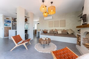 A modern living room with a sofa, wooden chairs, a round coffee table, and pendant lights. - Villa "Casa Rocas" with Mountain View, Private Pool & Wi-Fi (Mijas)