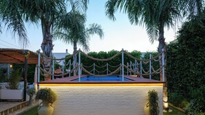 A swimming pool with a rope barrier, surrounded by palm trees and a brick wall.