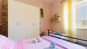 Una camera da letto con un letto, un armadio, uno scaffale con oggetti decorativi e una finestra con tende.