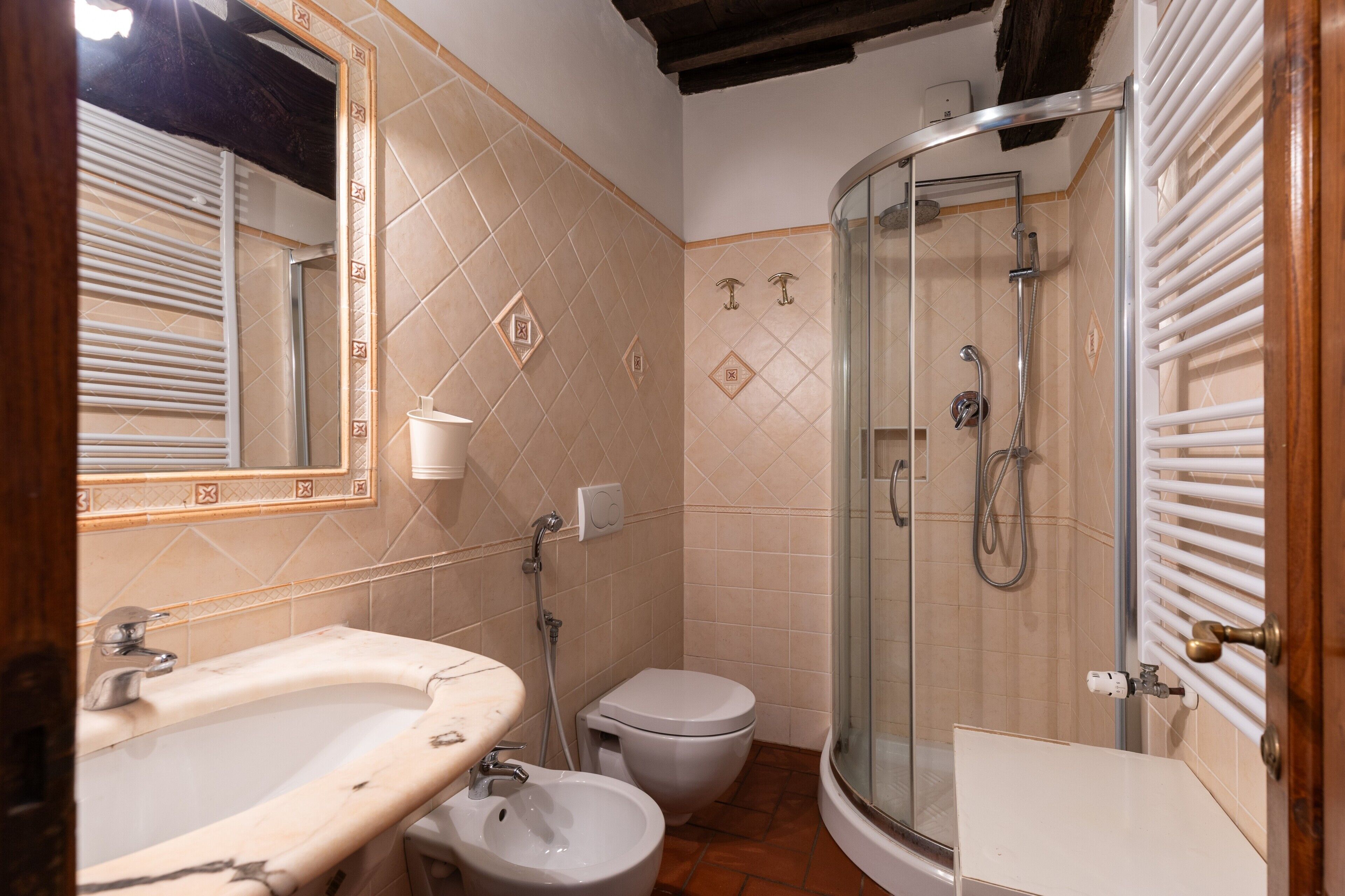 A bathroom with a bathtub, a toilet, a bidet, and a glass-enclosed shower area.