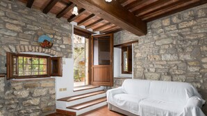 A stone-walled room with a white sofa, wooden beams, and a window with a view. - Villa 'La Petrosa' with Private Pool, Private Garden and Balcony (Radda in Chianti)