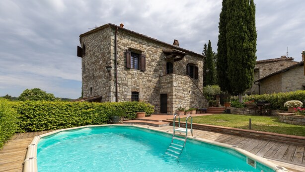 A stone building with a swimming pool, wooden deck, and a tall tree. - Villa 'La Petrosa' with Private Pool, Private Garden and Balcony (Radda in Chianti)