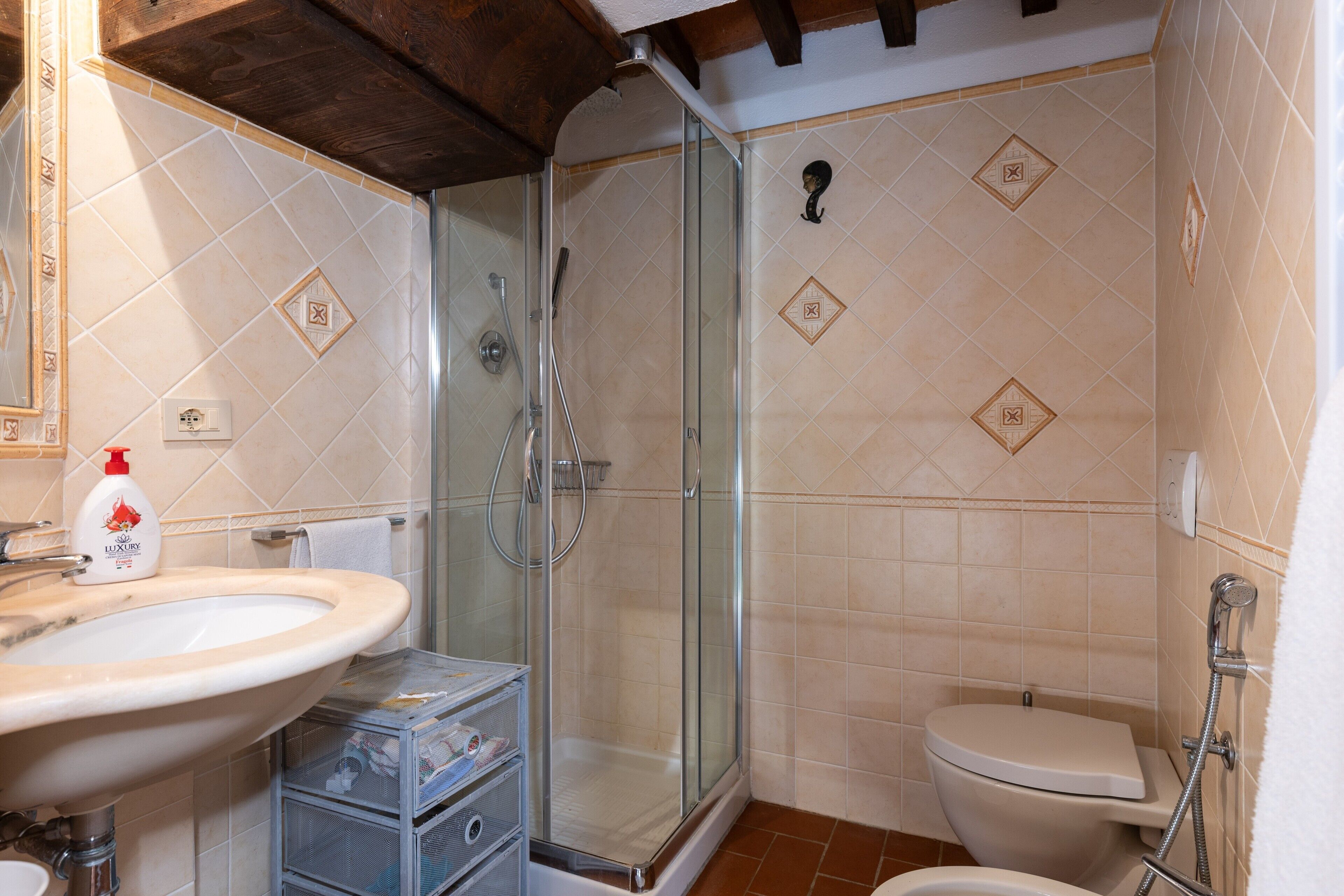 Een badkamer met een douche met glazen wand, een wastafel en een toilet.