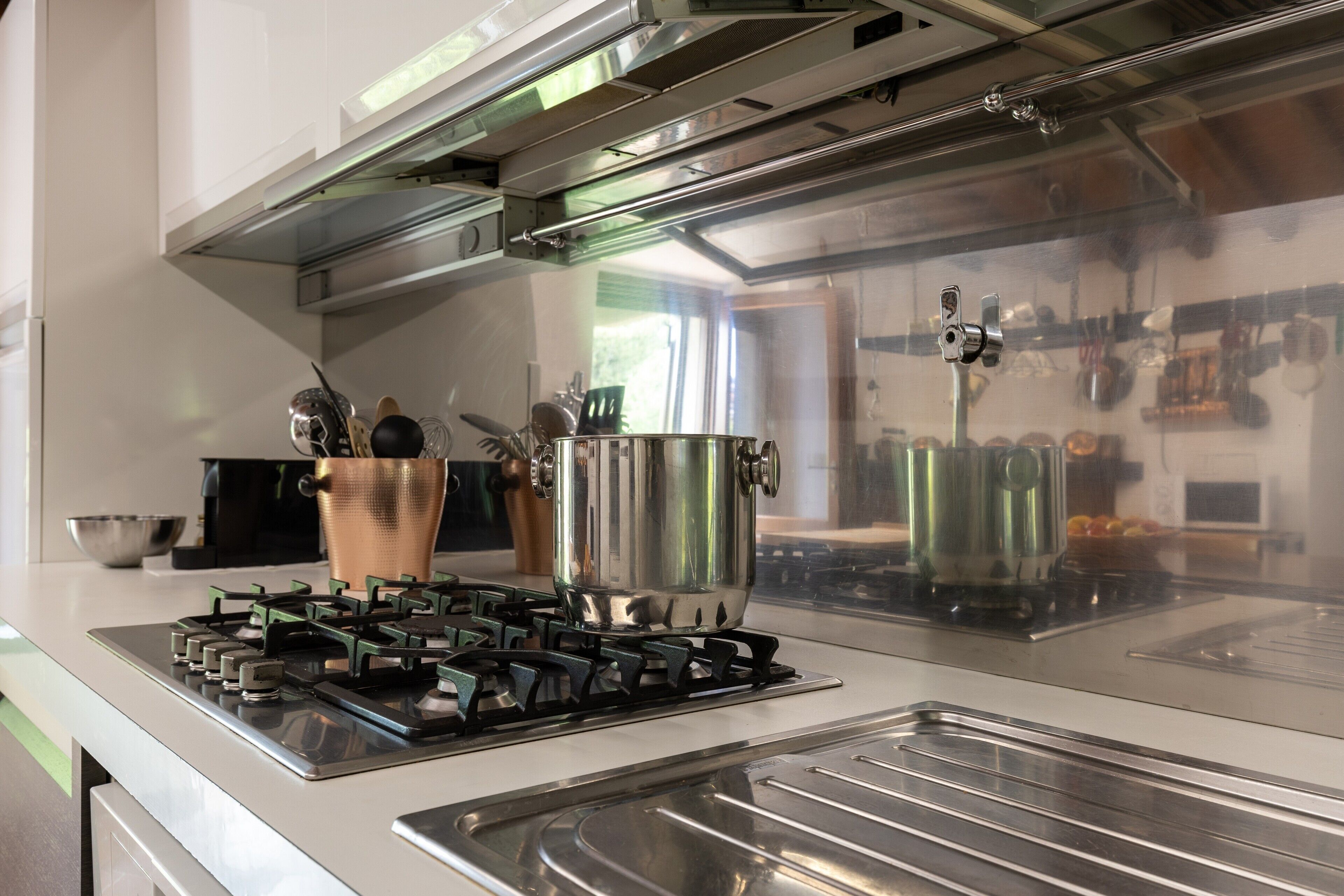 Une cuisine équipée d’appareils électroménagers en acier inoxydable, d’une cuisinière à gaz et d’une casserole posée sur le plan de travail.