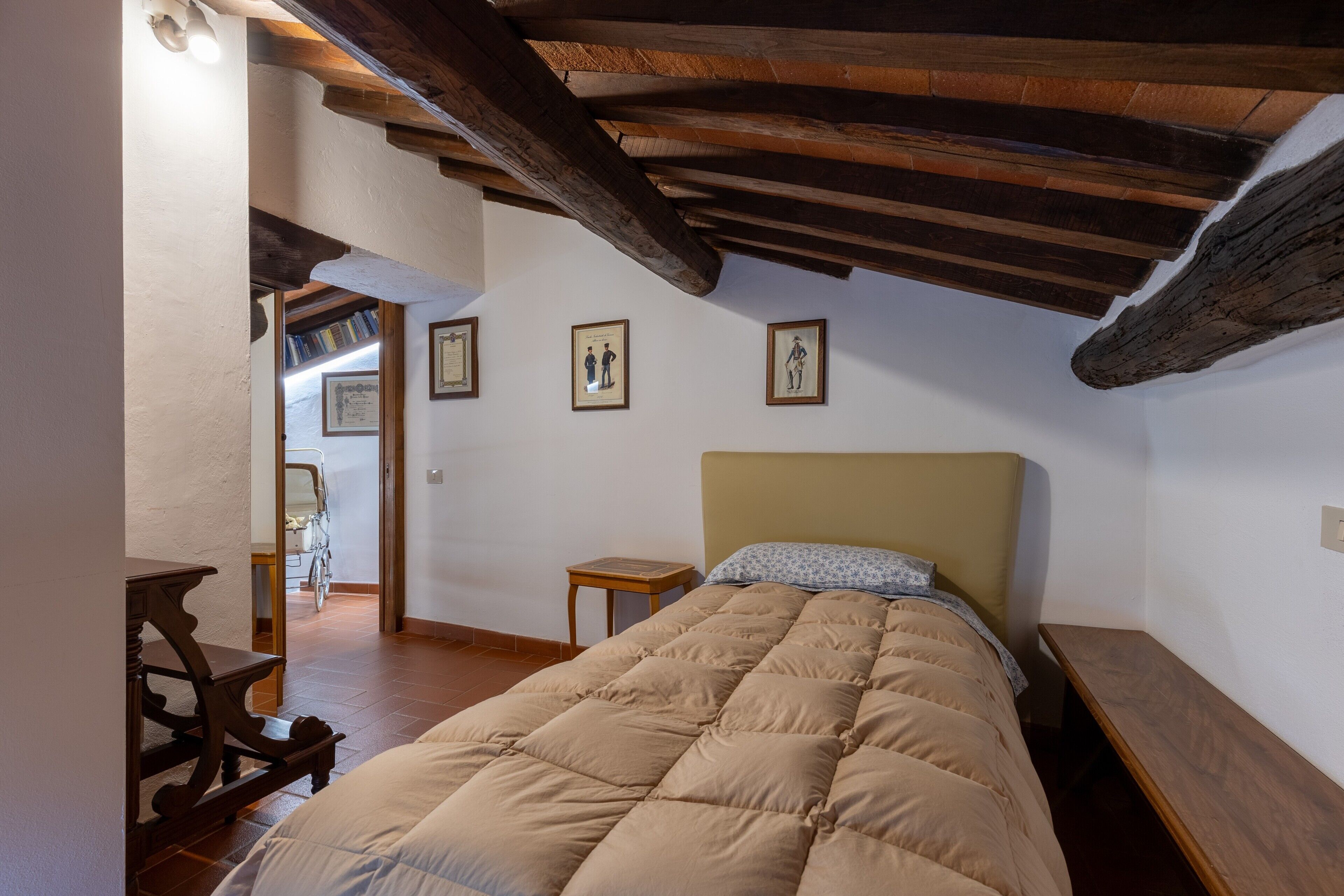 A bedroom with a bed, wooden headboard, a small wooden table, and a bench.