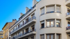 A multi-story building with balconies, large windows, and a curved facade.