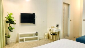 A bedroom with a bed, a desk, a chair, a potted plant, and a TV mounted on the wall. - 6 person single house (Taitung)