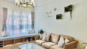 A cozy living room with a sofa, a coffee table, and a window with sheer curtains. - 6 person single house (Taitung)