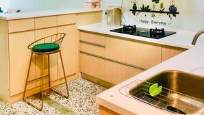 A compact kitchen with a white countertop, a stainless steel sink, a gas stove, and a small stool. - 6 person single house (Taitung)