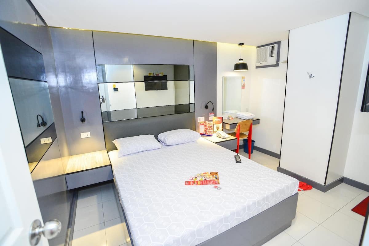 A modern bedroom with a large bed, a desk, and a wardrobe.