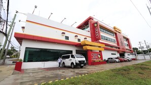 A hotel with a red and white facade, a large garage, and several parked cars. - Hotel Sogo Davao (Davao)